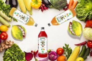 Bouteilles de jus de baobab bio BARIBA gingembre, citron et hibiscus entourees de fruits et legumes de saison